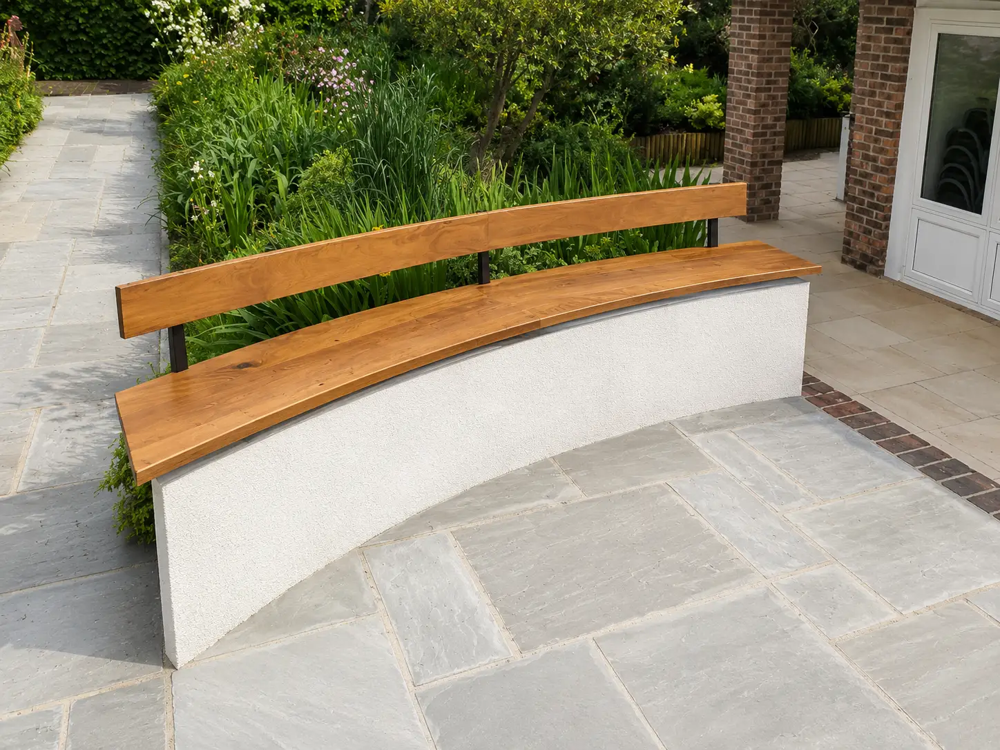 Curved oak garden bench on a rendered base, set on a Sussex stone patio against planting