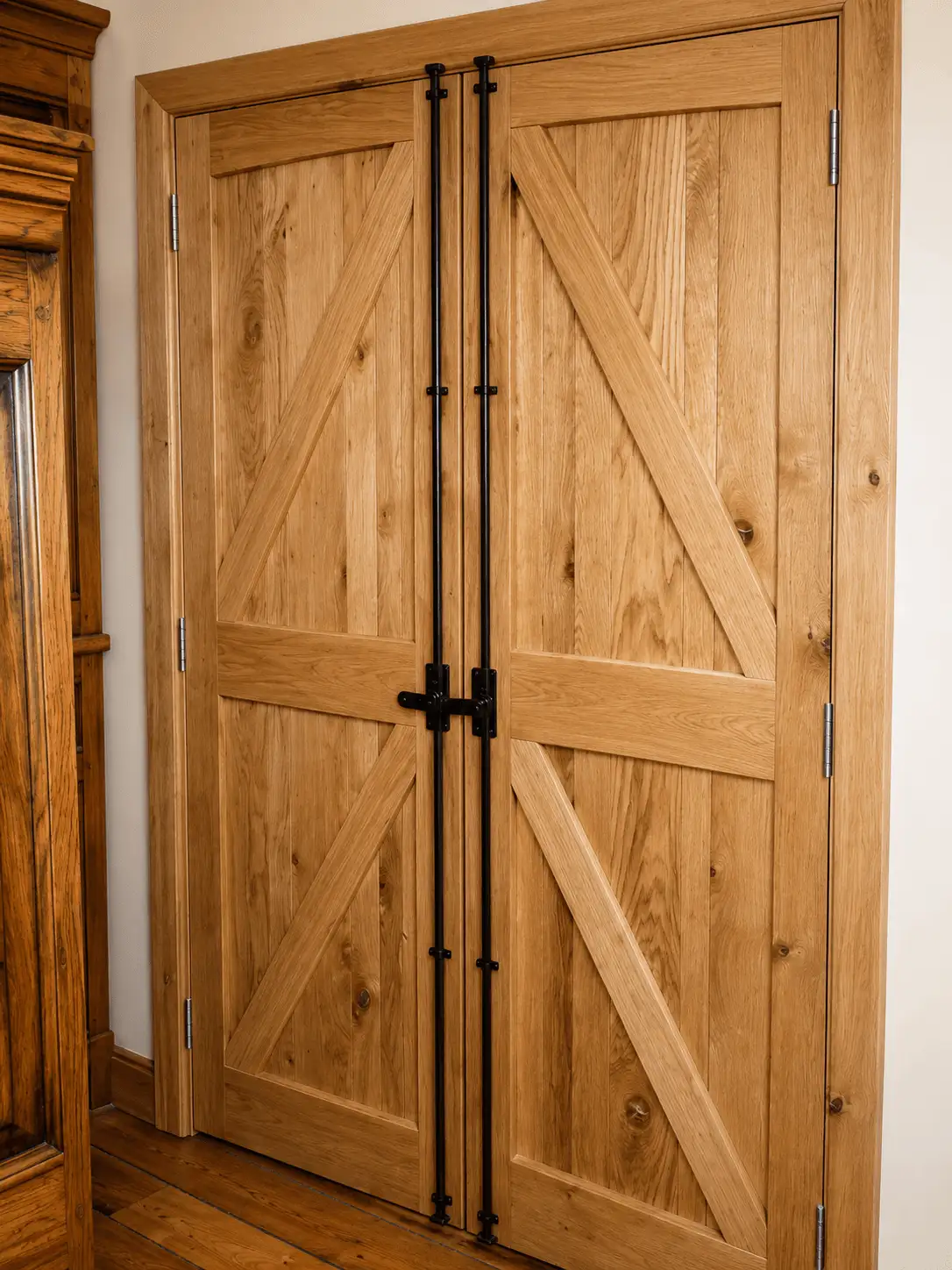 Oak ledged-and-braced double doors with black espagnolette ironmongery in a panelled room