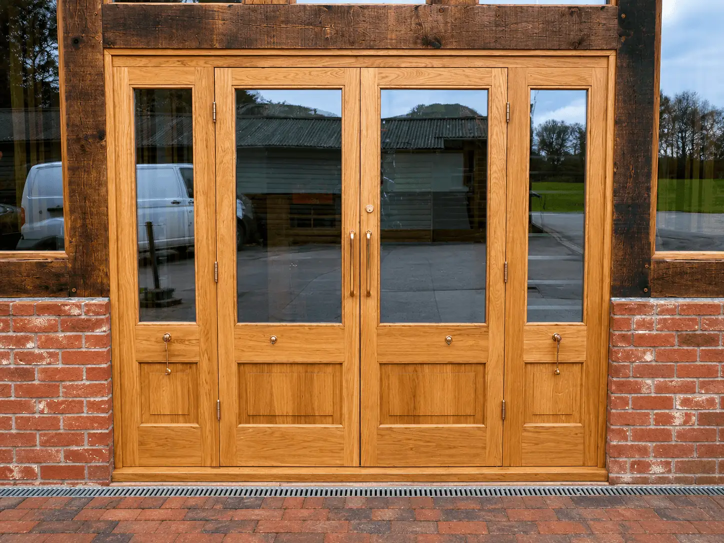 Oak glazed French door set with two central opening doors and matching glazed side panels, in a brick opening under an oak lintel