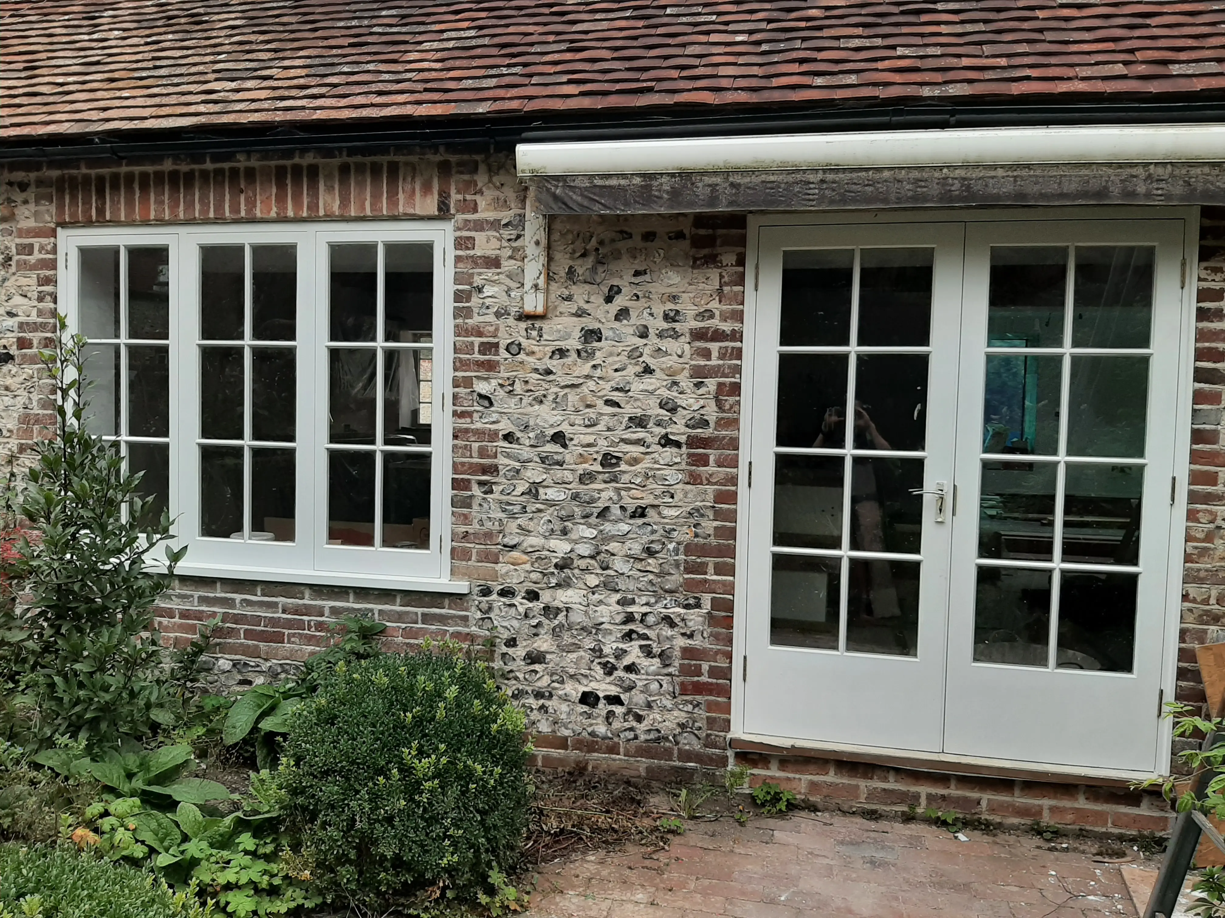 Pair of cream French doors with sash windows on a Sussex flint cottage