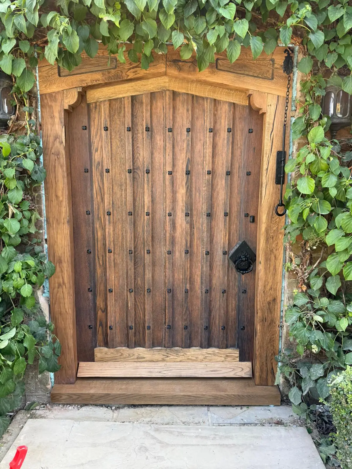 Hand-made studded oak arched door in a period stone surround