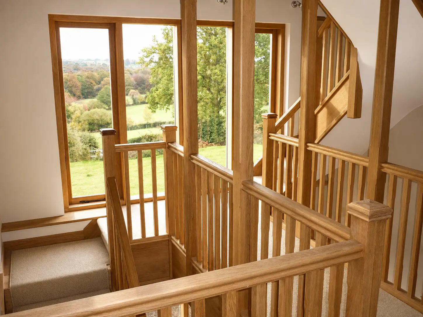 Oak galleried landing staircase with square spindles and a picture window over the garden