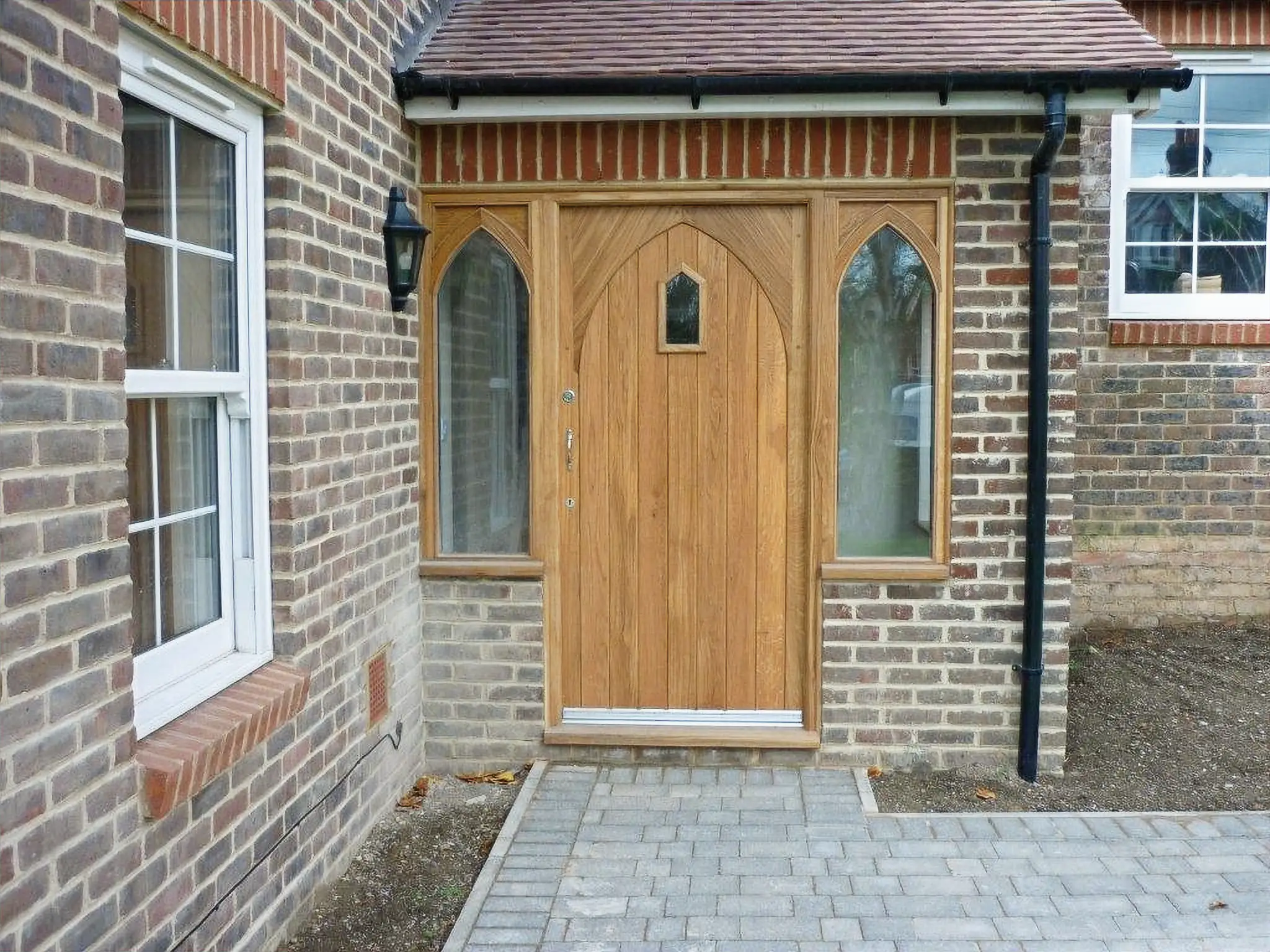 Restored oak Gothic-arch porch door in a tiled entrance