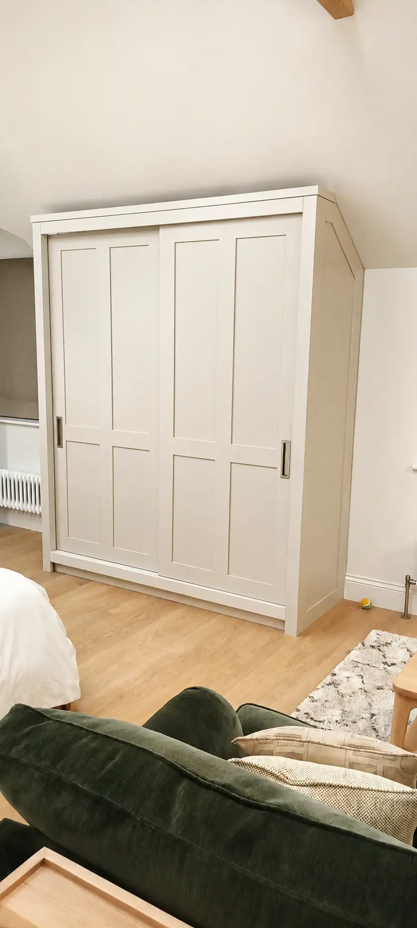 Cream painted shaker sliding-door fitted wardrobe in a loft bedroom