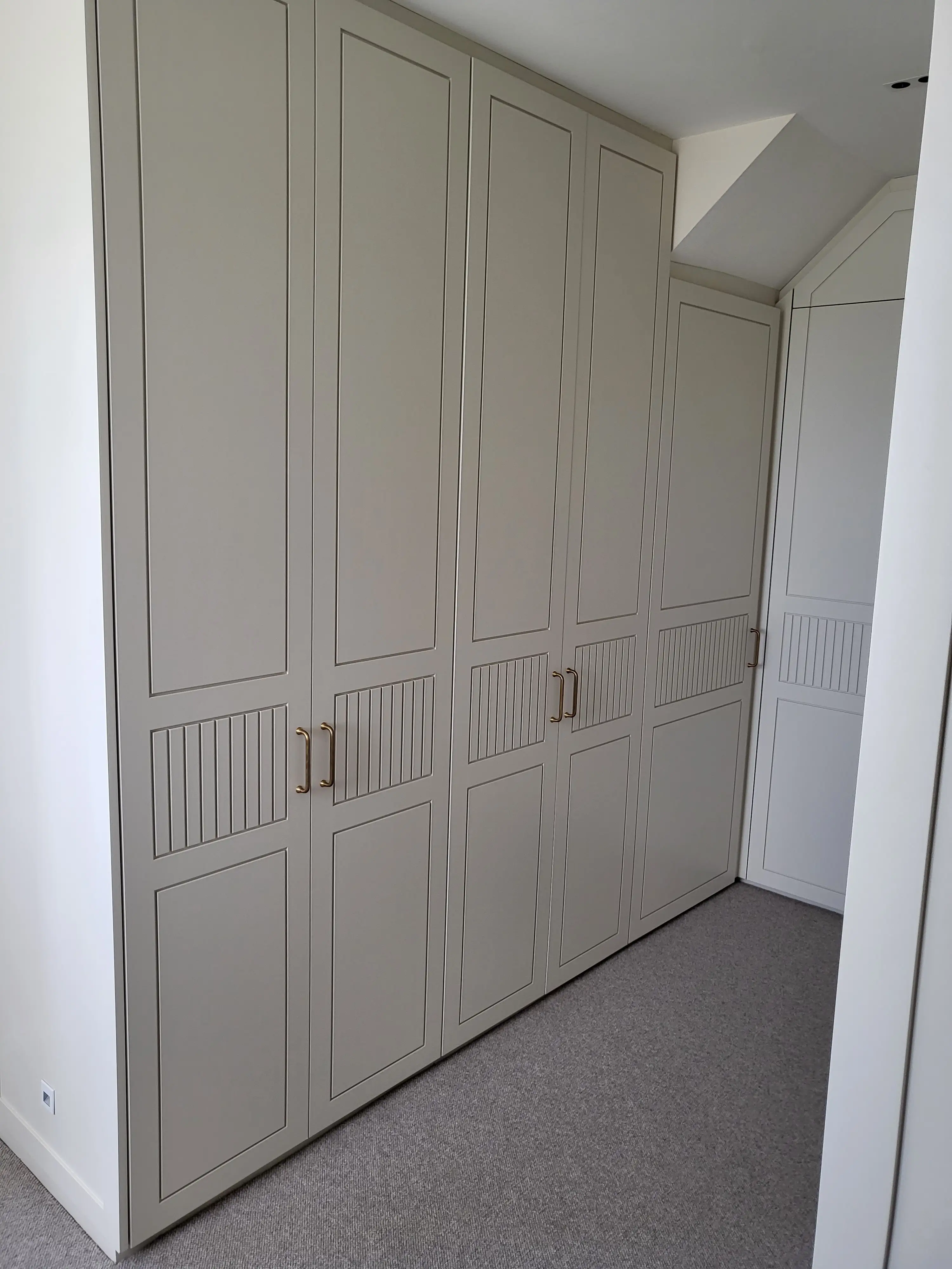 Bespoke fitted shaker-style wardrobes in soft warm grey with brass cup handles