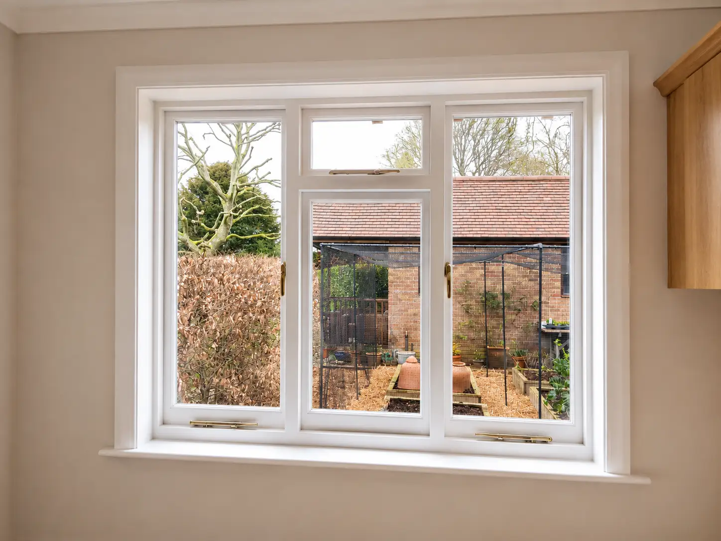 Cottage casement window installed, interior view looking out to garden, brass stays and white painted frame