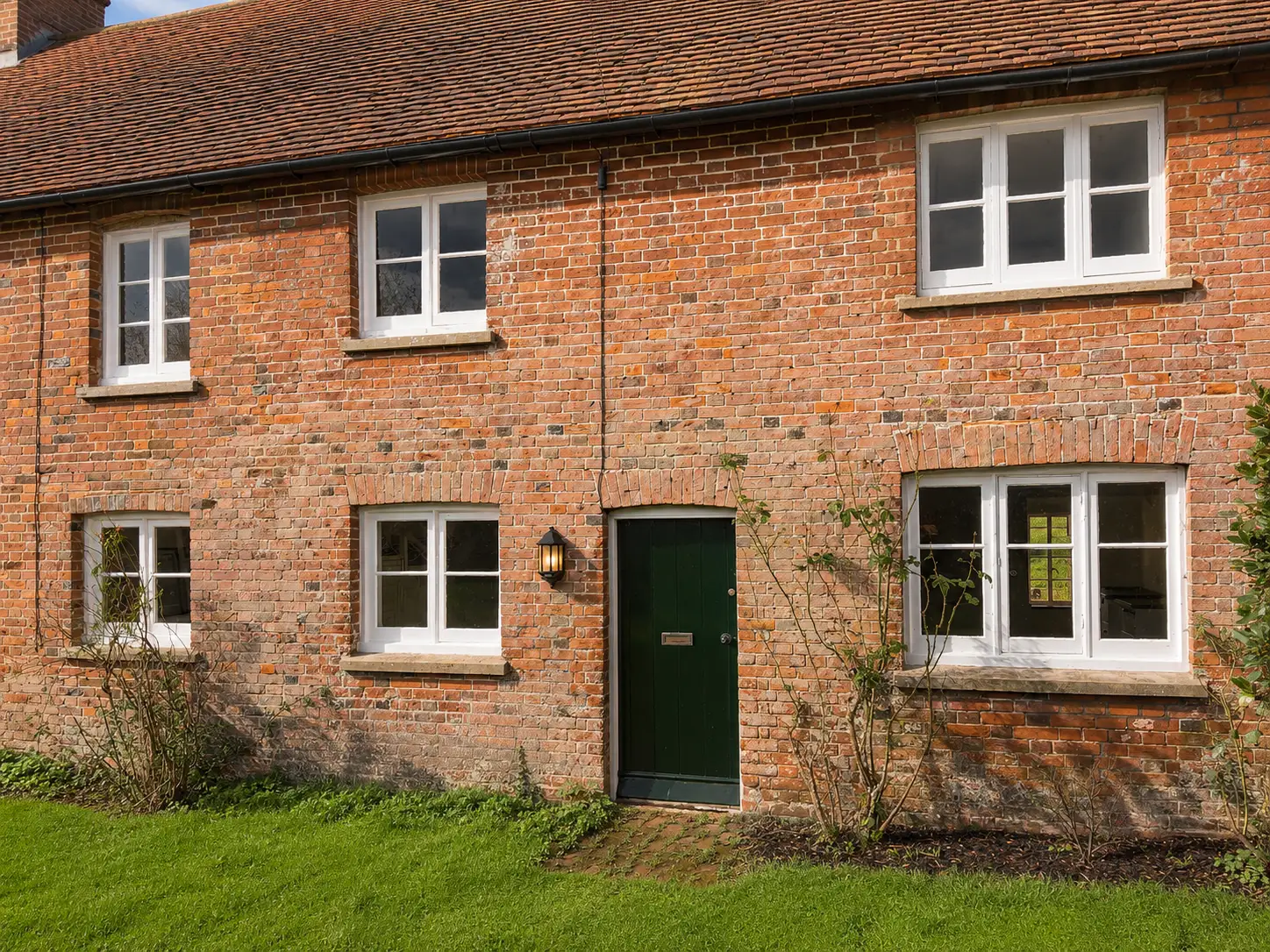 Period red-brick cottage exterior with white sash and casement windows installed by Forest Joinery