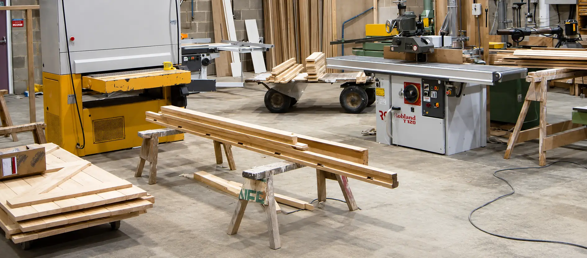 Inside the Forest Joinery workshop on Bell Lane, Uckfield, with timber on trestles and saw benches